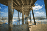 Man surfs from under the pier.